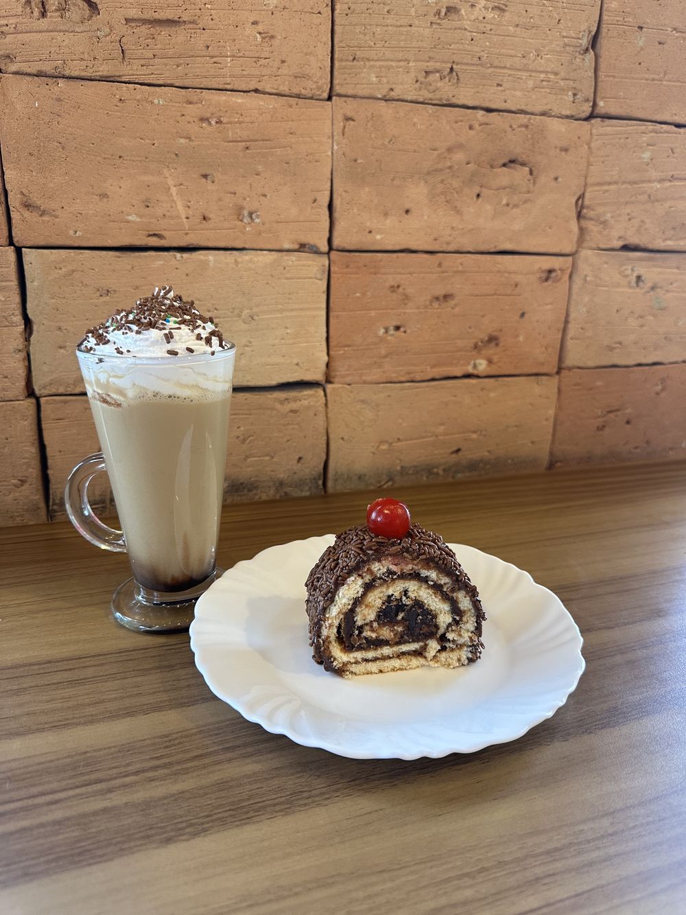 Café gelado com chantilly, servido com fatia de rocambole de chocolate