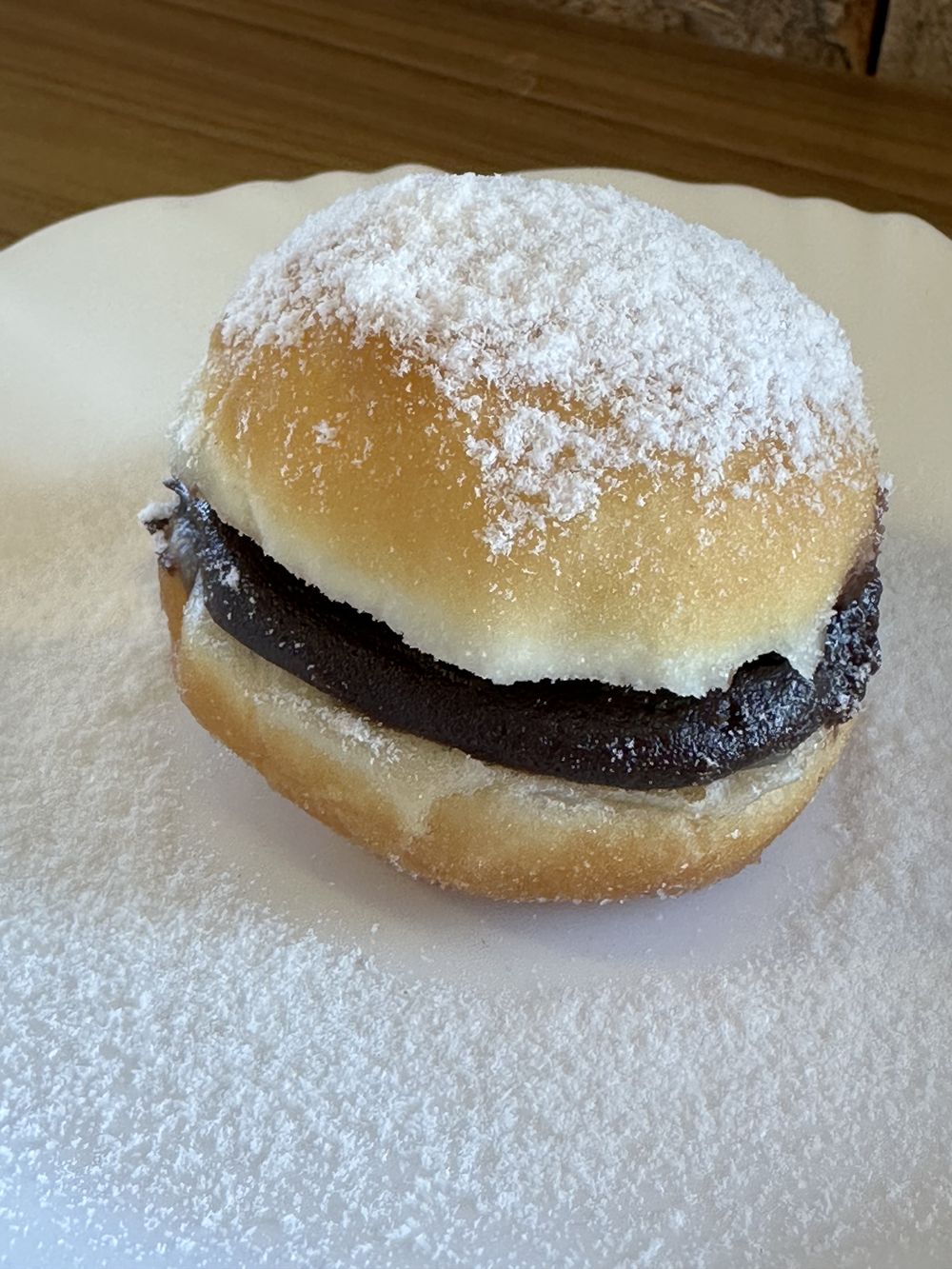 Sonho recheado com chocolate, coberto com açúcar de confeiteiro